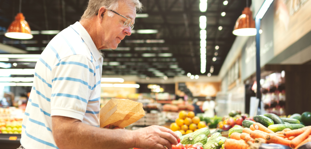 Baby Boomer man grocery shopping in a Canadian supermarket, reading nutrition labels in the aisle